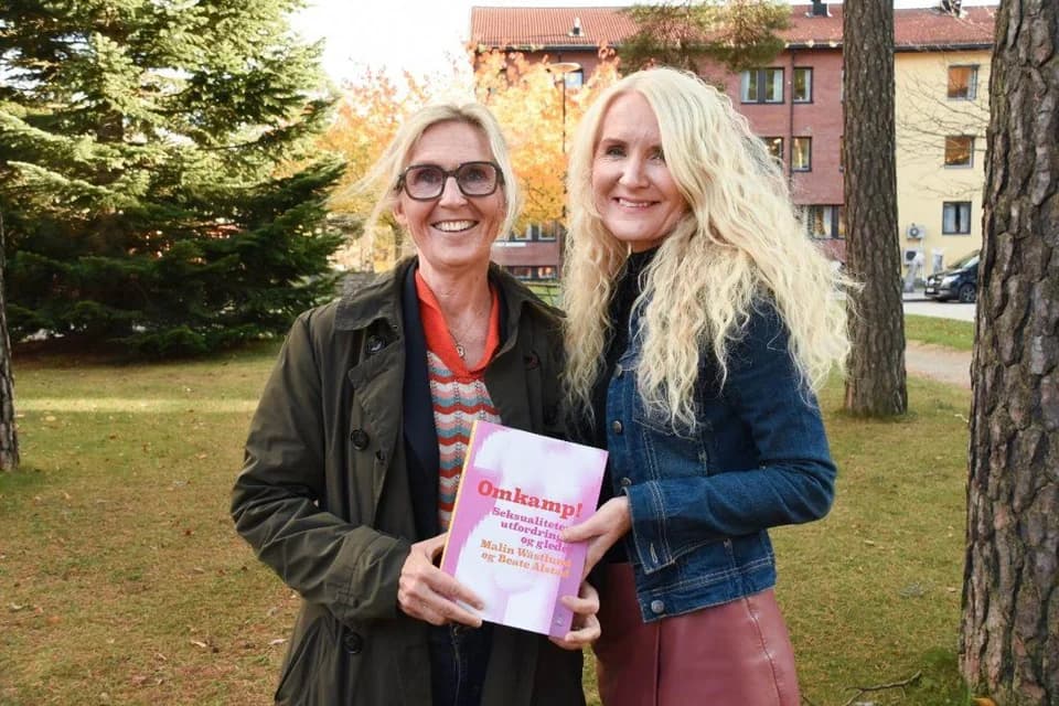 Two women holding the book Omkamp